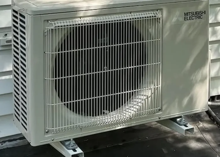 Outdoor Mitsubishi Electric air conditioner condenser unit with protective grille and large fan, mounted on the house exterior.